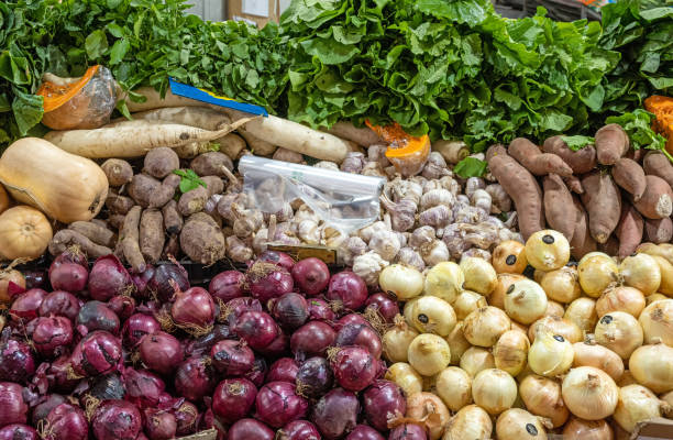 Different kinds of onions and potatoes for sale at a market
