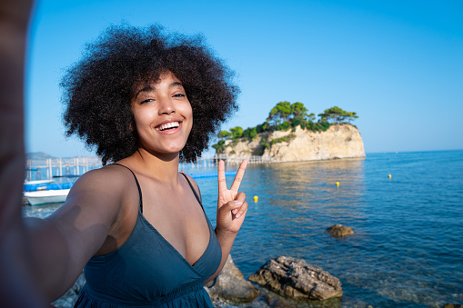 Smiling young afro woman   taking selfie in front of beautiful nature scene in Zakynthos Greece