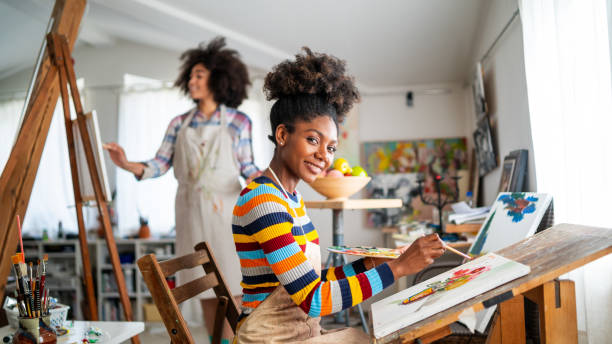 istock Smiling afro female fine artists drawing in studio 1382832660