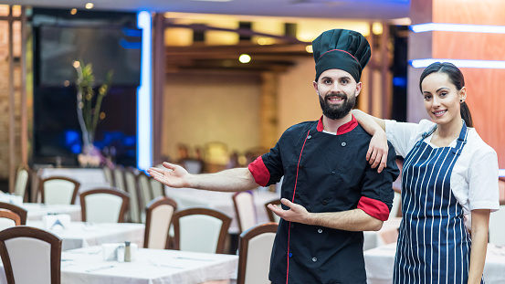 Professional cooks welcoming guests in restaurant