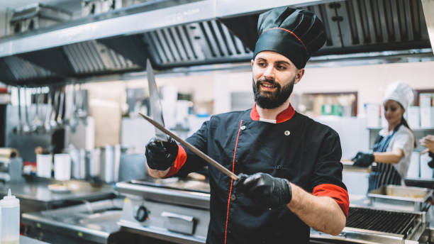 istock Male chef in the restaurant kitchen sharpening his knives 1382835869