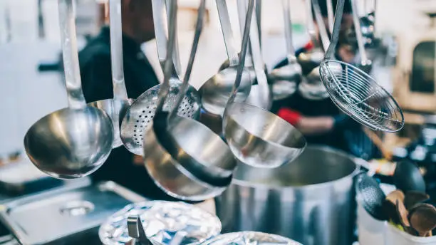 Kitchen detail, utensils for cooking hanging with hooks on the wall