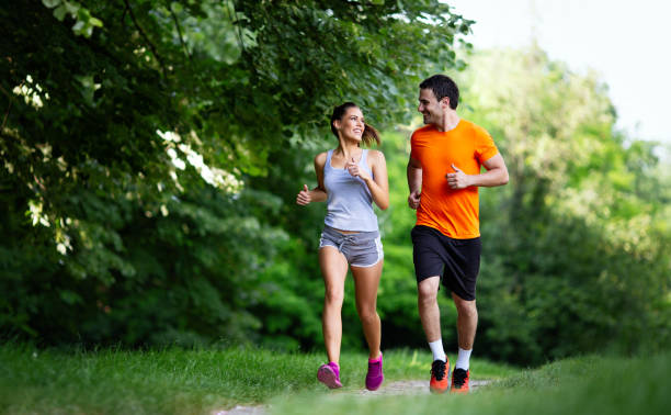 ritratto di persone felici in forma che corrono insieme le nostre porte. coppia sport sano lifetsyle concetto - correre foto e immagini stock