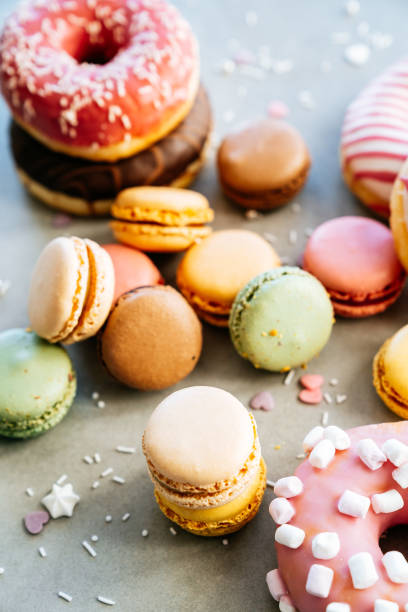 Colorful french macaroons and donuts on a concrete background.