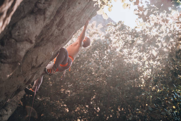 Young man climbing on a wall with blue sky on the background