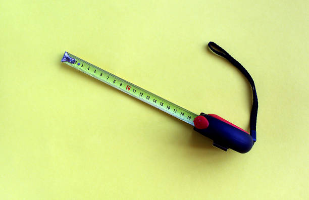 istock on a yellow background lies a construction tape measure. 1382901256