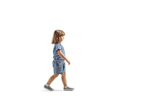 Full length profile shot of a little girl walking isolated on white background