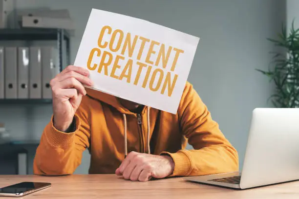 Content creation, man holding paper in front of his face in home office interior, selective focus