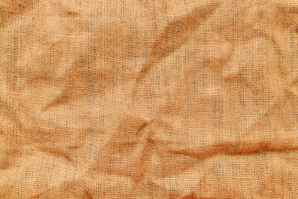 Texture of jute canvas fabric as background, top view of crumpled creased material