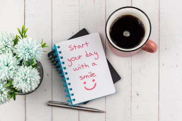 Start your day with a smile text on note pad with a cup of coffee and flower flat lay stock photo