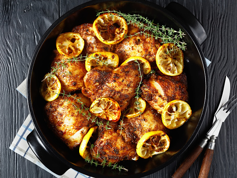 Lemon Thyme Braised Chicken Thighs in a black ceramic pan, close-up, flat lay