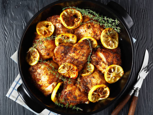 Braised Chicken Thighs in a ceramic pan Lemon Thyme Braised Chicken Thighs in a black ceramic pan, close-up, flat lay braised stock pictures, royalty-free photos & images