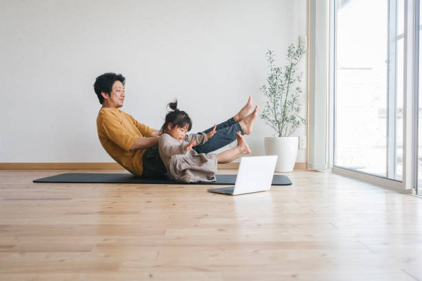 Father and daughter exercising at home with watching tutorials with laptop