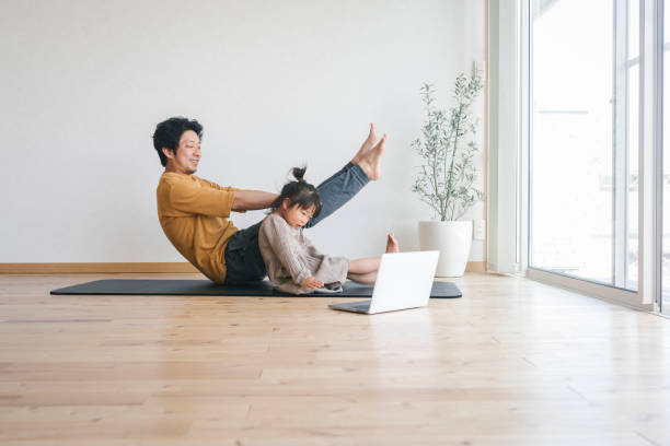 istock Father and daughter exercising at home with watching tutorials with laptop 1382907509
