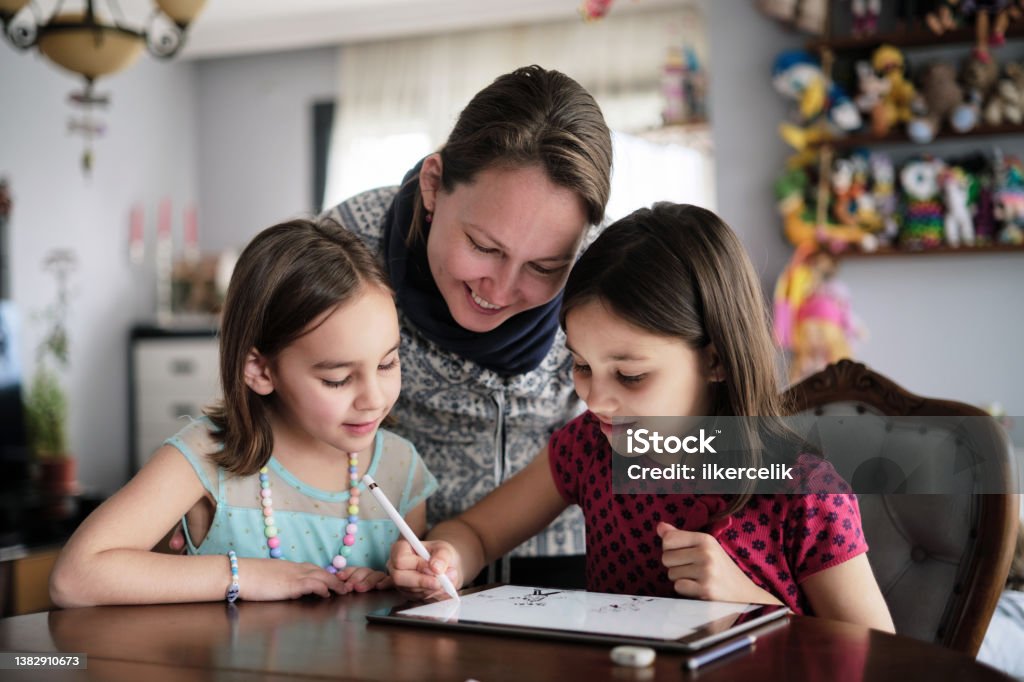 Mother And Daughters Painting Picture On Digital Tablet Using Digitized Pen At home Child Stock Photo