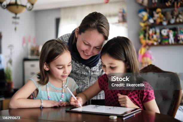 Mother And Daughters Painting Picture On Digital Tablet Using Digitized Pen At Home Stock Photo - Download Image Now