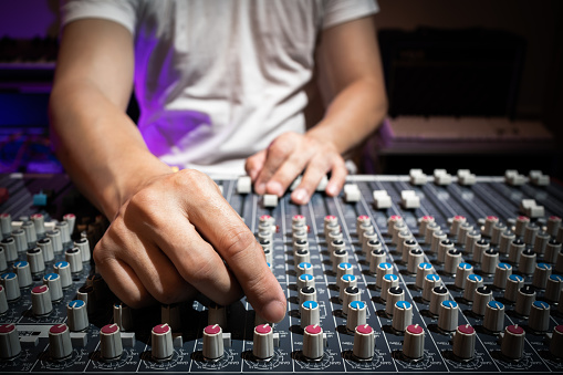 sound engineer hand adjusting eq knobs on audio mixing console. recording and broadcasting concept