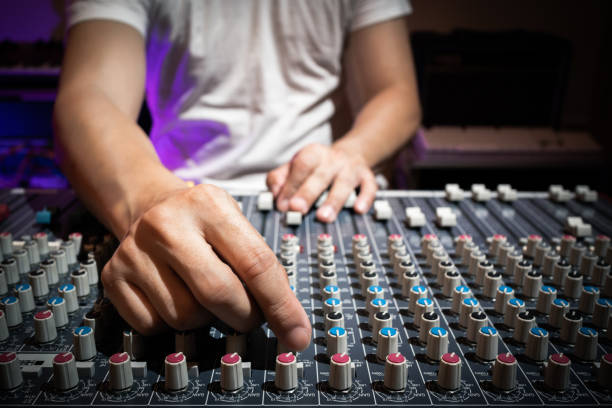 sound engineer hand adjusting eq knobs on audio mixing console. recording and broadcasting concept stock photo