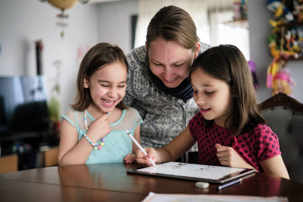 istock Mother And Daughters Painting Picture On Digital Tablet Using Digitized Pen At home 1382914451