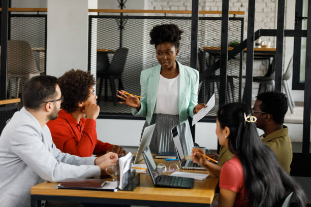 istock Confident young businesswoman discussing upcoming projects with colleagues while leading a meeting 1382915904