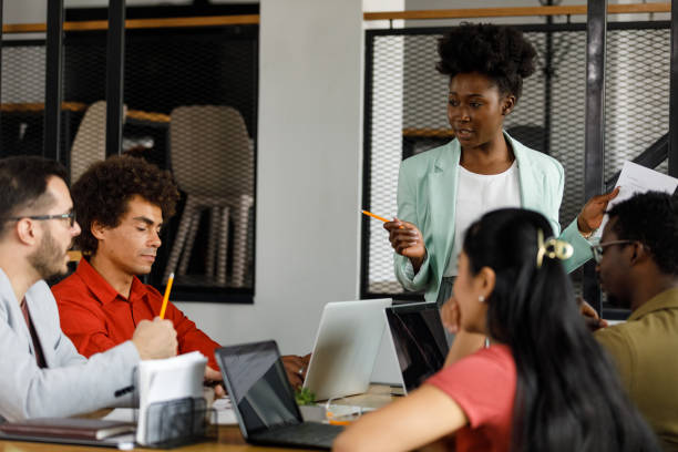 istock Female manager leading a project meeting at the office, discussing project reports with employees 1382915907