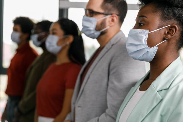 istock Business people in protective face masks standing in a row, looking away 1382916177