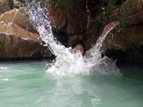 girl splashes around in a natural pool in the Dead Sea desert area