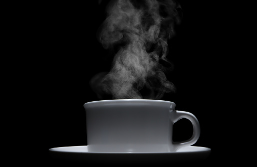 white ceramic coffee cup with floating smoke. isolated on a black background