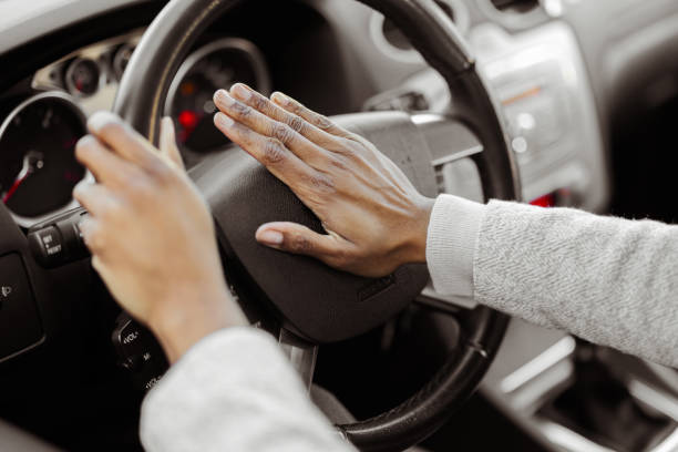 Hand Pushing on Steering Wheel Honking Horn Closeup inside the vehicle of hand pushing on steering wheel honking horn brass instrument stock pictures, royalty-free photos & images