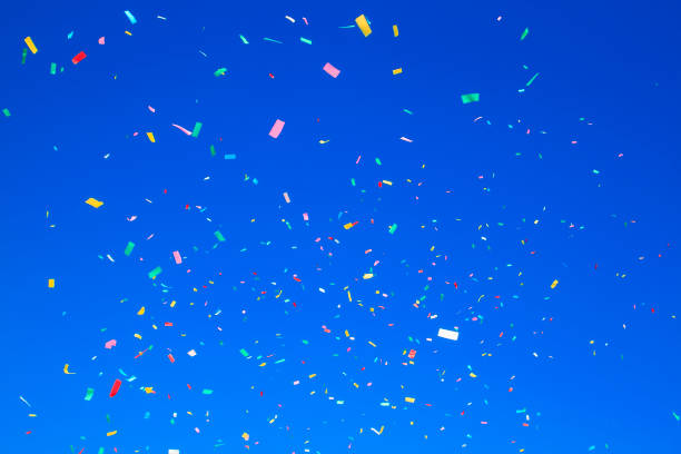 istock multicolored confetti on clear blue sky background. Concept of h 1382949796