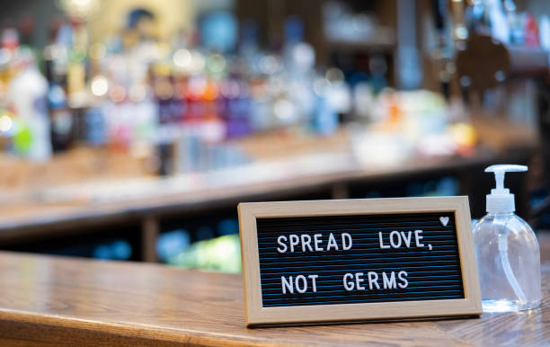 istock Spread Love Not Germs Sign Next To Hand Sanitiser Bottle On Bar Counter 1382950876