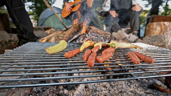 Sausages and Courgette cooking on barbecue grill in forest.