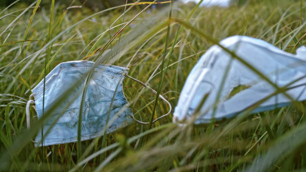Close-up of face mask lies on high grass.