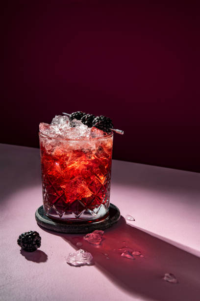 boisson cocktail froide d’été avec de la glace garnie de mûre sur de la violette spectaculaire - cocktail alcohol red martini glass photos et images de collection