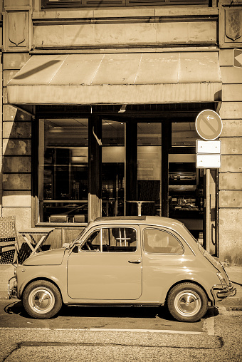 Classic car parked in front of a bakery on a street corner in the city of Hamburg. Sepia toned vintage photo with a retro feel.