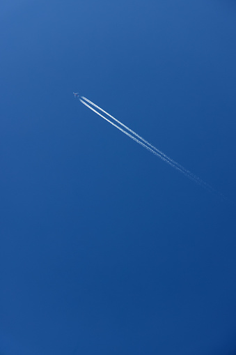 Flugzeug mit Kondensstreifen hoch am Himmel