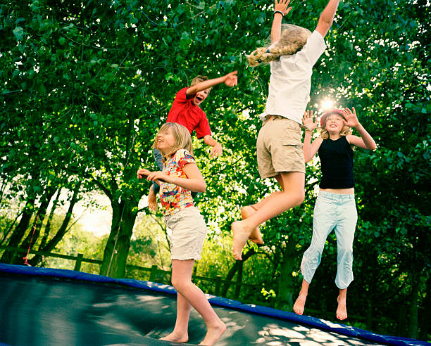 cuatro niños del salto del sobre trampolín - child group of people teenager sibling fotografías e imágenes de stock