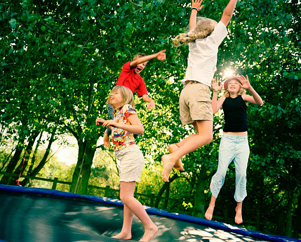 4 children leaping on trampoline  jumping teenager fun group of people stock pictures, royalty-free photos & images