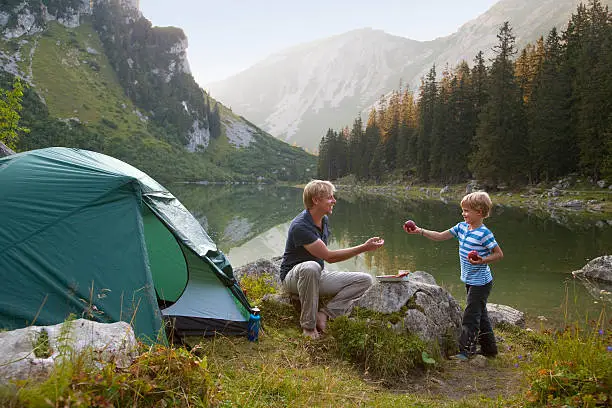 Photo of Father and son eating at campsite