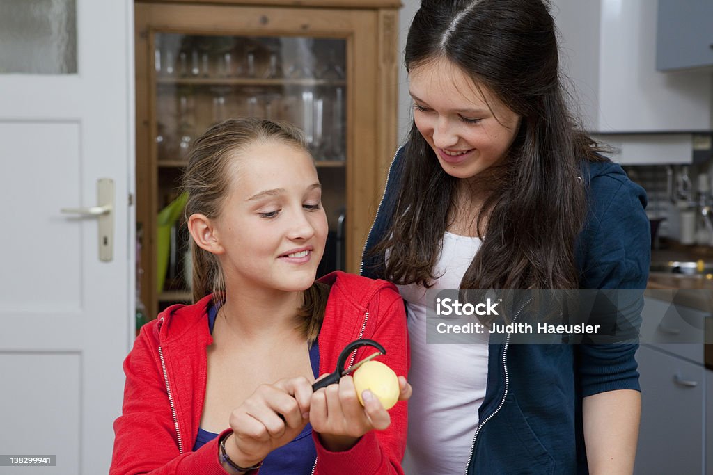 Girls peeling potatoes in kitchen  12-13 Years Stock Photo