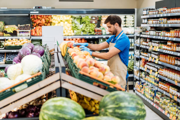 istock Employee in supermarket arranging fresh fruit 1383001849