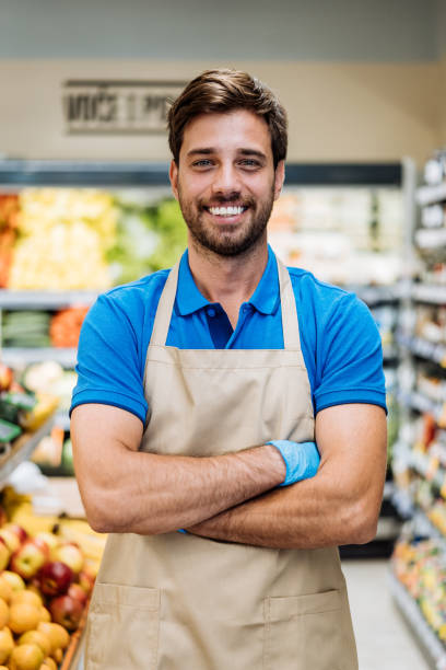 istock Employee in supermarket arranging fresh fruit and looking at camera 1383004139
