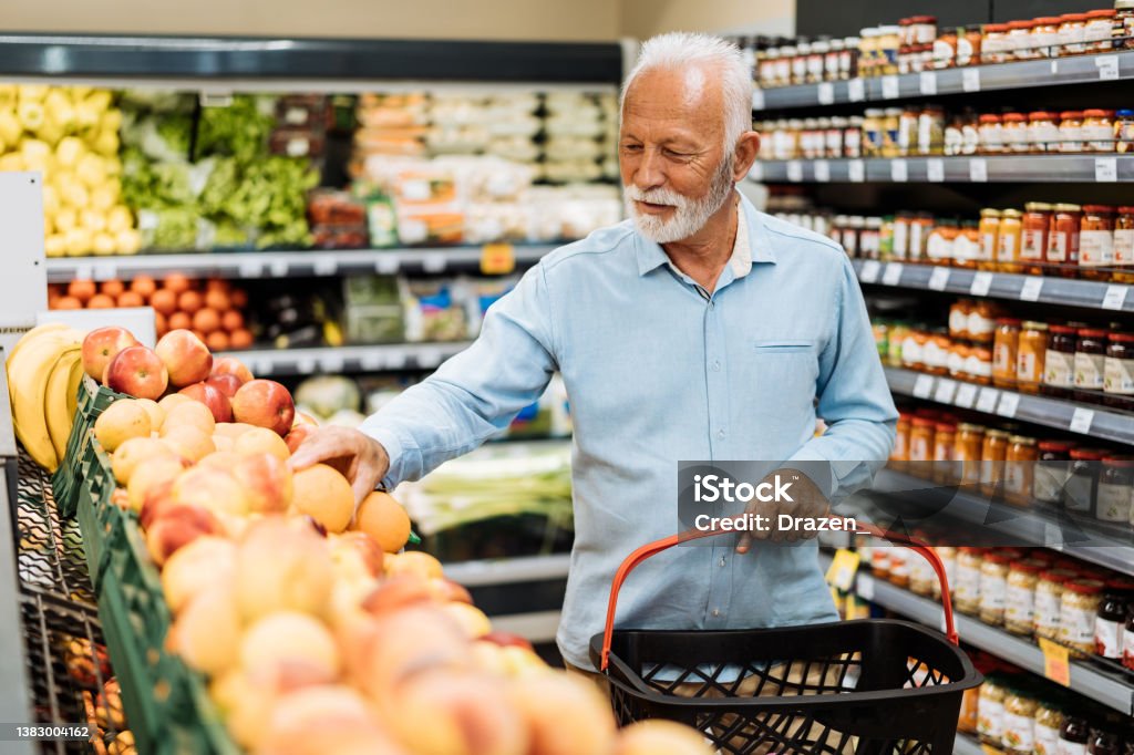 Retired man buying groceries - fruits and vegetables People buying groceries in supermarket Supermarket Stock Photo