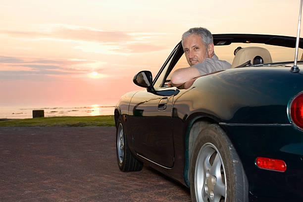 mann sitzt im cabrio auf die küste - outdoors car convertible wealth stock-fotos und bilder