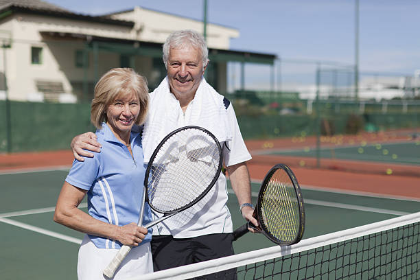 älteres paar umarmen auf den tennisplatz - tennis active seniors healthy lifestyle senior men stock-fotos und bilder