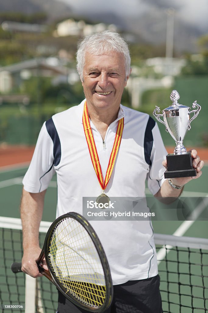 Older man with trophy on tennis court  Trophy - Award Stock Photo