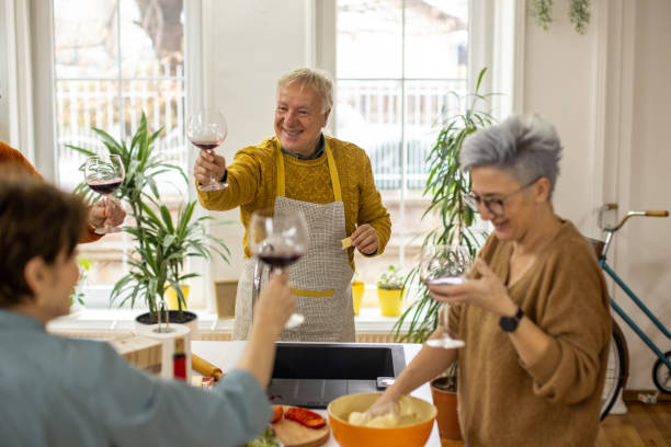 istock Carefree senior friends toasting with red wine while making lunch in the kitchen 1383008321