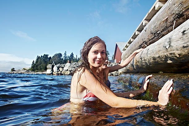 teenage girls climbing pier - sweden summer swimming lake - fotografias e filmes do acervo