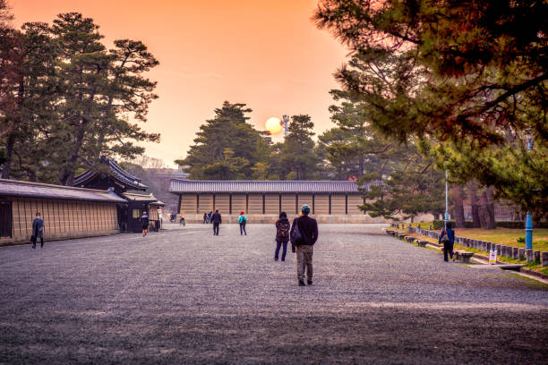 26 march 2019 - Kyoto, Japan: Japanese people walking and riding bicycle in in Kyoto Gyoen park, in front of the Imperial palace at sunset