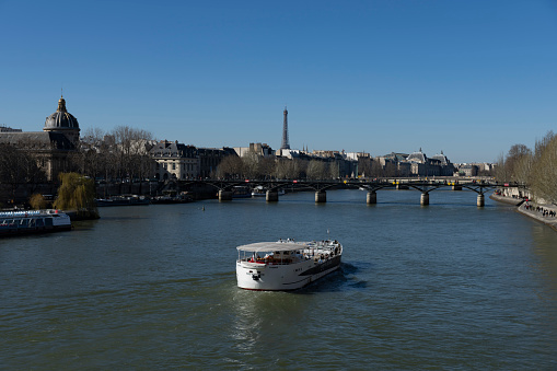 2022 River Seine cruiser in Paris, France. There are tourists and locals outside in the winter sunshine.